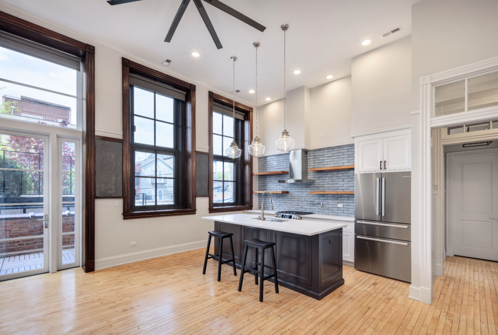 The apartments are enriched with a multitude of recycled materials sourced from the school, such as repurposed wood joists that now serve as open kitchen shelving.