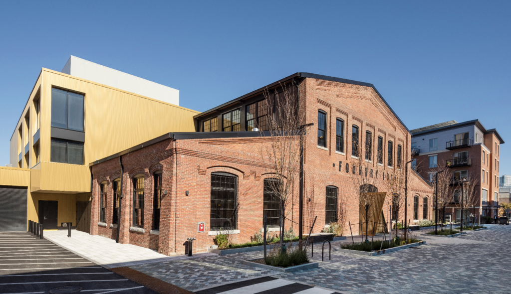 A new addition clearly stands out from the original brick with corrugated, brass-colored cladding that speaks to the metalsmithing that once took place within the building.