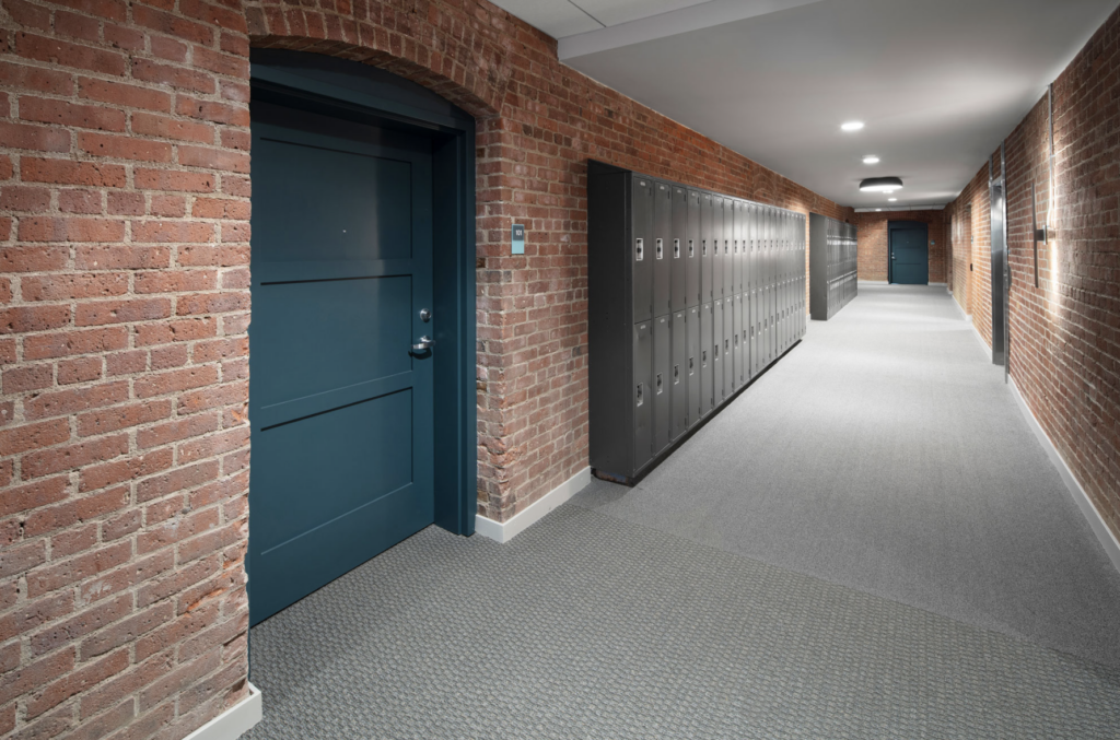 Corridor walls are exposed brick with painted lockers located throughout.