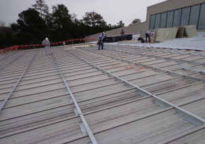 The roofing contractor elected to recover the building roof using specially fabricated steel sub-purlins, which permitted the installation of a new metal roof without removal of the old metal roof.
