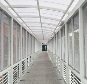 Working with an existing precast concrete panel bridge, the manufacturer fabricated the walkway columns, beams and supporting roof structure, as well as the mesh and louvers along the walkway’s sides.