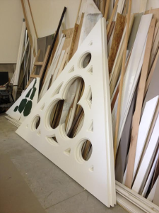 At the Nugent Builders Inc., millwork shop in Rockford, Mich., triangular PVC pediments, each measuring 10 feet on a side, await shipment to the project site. Sharp edges and accurate dimensions closely match the original appearance of the damaged components.